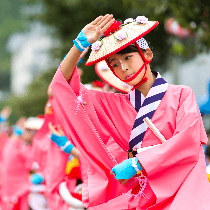 ピンクの伝統衣装と花飾りの笠を身につけた踊り手がポーズを取っている様子